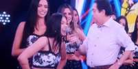 Fausto Silva bate com microfone na boca de uma das bailarinas do programa.  Foto: Instagram/@karinabarros_ / Estadão Conteúdo