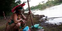 Indígena da tribo Pataxó Hã-hã-Hãe observa peixe morto na margem do rio Paraopeba  Foto: Adriano Machado / Reuters