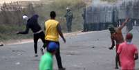 Manifestantes atiram pedras em direção às forças militares venezuelanas  Foto: Ricardo Moraes / Reuters