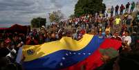 Manifestantes seguram bandeira da Venezuela durante protesto favorável ao governo na fronteira entre o país e o Brasil
24/02/2019 REUTERS/Bruno Kelly  Foto: Reuters