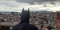 Jovem fantasiado de Batman olhando para o horizonte de casas do Capão Redondo.  Foto: PerifaCon / Divulgação / Estadão