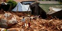 Crianças carregam água após os efeitos do cyclone Idai em Moçambique, Zimbábue. 22/3/2019. REUTERS/Philimon   Foto: Reuters