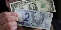 Homem segura notas de 1 dólar e 2 reais
13/12/2001
REUTERS/Gregg Newton  Foto: Reuters
