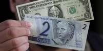Homem segura notas de 1 d&oacute;lar e 2 reais
13/12/2001
REUTERS/Gregg Newton  Foto: Reuters
