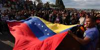 Venezuelanos seguram bandeira do país durante manifestação de apoio ao governo de Nicolás Maduro na fronteira com o Brasil, em Pacaraima, em Roraima
24/02/2019
REUTERS/Bruno Kelly  Foto: Reuters