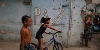 Crianças brincam diante de muro cravejado de tiros  Foto: REUTERS / BBC News Brasil