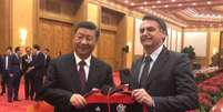 Bolsonaro posa ao lado de presidente da Chinacom o agasalho rubro-negro (Foto: Reprodução/Twitter)  Foto: LANCE!