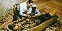 Arqueólogo britânico Howard Carter e um trabalhador egípcio examinam um caixão feito de ouro maciço dentro da tumba  Foto: Griffith Institute / BBC News Brasil