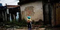 A girl holds her brother at the entrance of their house at a favela, or a slum, in Rio de Janeiro, Brazil June 24, 2016. Picture taken June 24, 2016. REUTERS/Nacho Doce - RC1EE125CC30  Foto: Reuters