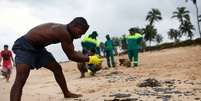 Moradores ajudam a limpar óleo da praias de Barra de Jacuipe, na Bahia  Foto: Lucas Landau / Reuters