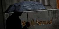 Homem caminha pela chuva em Wall Street do lado de fora da Bolsa de Nova York (NYSE), EUA. 09/10/2019. REUTERS/Brendan McDermid  Foto: Reuters