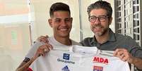 Bruno Guimarães aparece segurando camisa do Lyon ao lado de Juninho Pernambucano  Foto: Divulgação/Twitter de JM_Aulas / Estadão Conteúdo