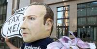 Um ativista usando máscara em referência ao presidente do Facebook, Mark Zuckerberg, protesta pedindo aumento de impostos sobre a empresa. 4/12/2018. REUTERS/Yves Herman  Foto: Reuters