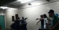 Policial aponta a arma para alunos da Escola Professor Emygdio de Barros  Foto: Reprodução Twitter / Estadão Conteúdo