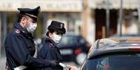 Policiais italianos usam máscara de proteção enquanto verificam se motorista tem razão válida para viajar durante bloqueio no país
21/03/2020
REUTERS/Yara Nardi  Foto: Reuters