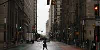 Mulher atravessa uma Broadway quase vazia no distrito financeiro, em meio ao surto da doen&ccedil;a do coronav&iacute;rus (Covid-19), Nova York, EUA
23/03/2020
REUTERS/Mike Segar  Foto: Reuters