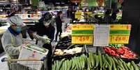 Pessoas com máscaras de proteção compram vegetais em supermercado em Wuhan
26/03/2020
REUTERS/Stringer  Foto: Reuters