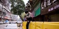 Jovem de máscara pula barreira de isolamento construída para separar prédios de rua em Wuhan
31/01/2020
REUTERS/Aly Song  Foto: Reuters