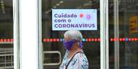 Idosa usa lenço como máscara de proteção contra o novo coronavírus enquanto passa por em agência bancária em Curitiba  Foto: GIULIANO GOMES / ESTADÃO CONTEÚDO