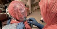 Roberts ajuda seus colegas a colocar sacos de lixo para proteger suas cabeças.  Foto: BBC News Brasil