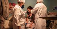 Confinada desde o último domingo, a doméstica Edilândia é amparada pelo médico Luiz Barbosa e enfermeira   Foto: DW / Deutsche Welle