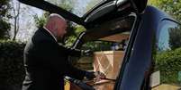 Funcionário de funerária coloca caixão na traseira de veículo na Inglaterra, em meio à pandemia do coronavírus. 22/4/2020. REUTERS/Molly Darlington  Foto: Reuters