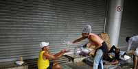 Voluntária despeja álcool gel na mão de homem durante ação de entrega de comida para pessoas em situação de rua no Rio de Janeiro
11/04/2020
REUTERS/Lucas Landau  Foto: Reuters