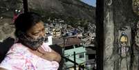 Uma mulher usa máscara protetora fica do lado de fora de sua casa, na favela da Rocinha, durante o surto de doença por coronavírus (COVID-19), no Rio de Janeiro  Foto: Ricardo Moraes / Reuters