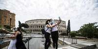 Amigas tiram fotos em frente ao Coliseu de Roma, na Itália: o turismo entre regiões ainda está proibido  Foto: ANSA / Ansa