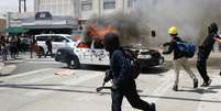 Oficiais da tropa de choque e manifestantes que atearam fogo em viaturas entraram em confronto em Los Angeles, n Califórnia  Foto: Getty Images / BBC News Brasil