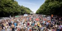 Poucas máscaras foram vistas em meio aos grupos que caminhavam do portão de Brandemburgo até o parque Tiergarten.  Foto: Reuters