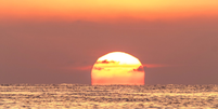 O sol pode ficar vermelho sobre o mar e com um céu laranja.  Foto: Getty Images / BBC News Brasil