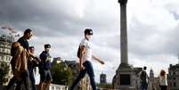 People wearing protective face masks walks through Trafalgar Square  Foto: Reuters / BBC News Brasil