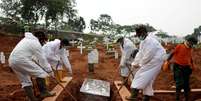 Coveiros trajando roupas de proteção fazem sepultamento em área destinada a vítimas do novo coronavírus em cemitério em Jacarta, Indonésia
24/09/2020
REUTERS/Willy Kurniawan  Foto: Reuters