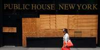 Mulher passa por bar fechado em Nova York. REUTERS/Carlo Allegri  Foto: Reuters