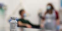 A test volunteer and medical worker behind a vial of the Oxford-AstraZeneca vaccine  Foto: John Cairns/University of Oxford HO / BBC News Brasil