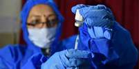 profissional de saúde com seringa e vacina  Foto: EPA / BBC News Brasil