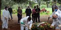 Parentes acompanham sepultamento de homem que morreu por Covid-19, em cemitério em São Paulo
REUTERS/Amanda Perobelli  Foto: Reuters