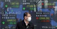 Homem usando máscara de proteção apaece em frente a painel eletrônico com cotações do mercado financeiro. 4/1/2021. REUTERS/Kim Kyung-Hoon  Foto: Reuters