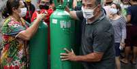 Parentes de pacientes com Covid-19 carregam cilindros de oxigênio
REUTERS/Bruno Kelly  Foto: Reuters