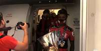 Bruno Henrique segura a taça na saída do avião (Foto: Reprodução/Flamengo)  Foto: Lance!