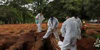 Coveiros vestindo traje de proteção enterram homem que morreu de Covid-19, no cemitério de Vila Formosa, em São Paulo
25/12/2020
REUTERS/Amanda Perobelli  Foto: Reuters