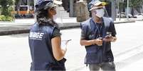 Dois agentes do censo usando máscaras e viseira no rosto  Foto: IBGE / BBC News Brasil