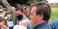 Jair Bolsonaro pega bebê nos braços durante viagem a Goianópolis; presidente voltou a dispensar o uso da máscara em compromisso público.  Foto: Reprodução/ Instagram/ Major Vítor Hugo / Estadão