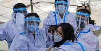 Grupo de trabalhadoras da saúde com equipamento de proteção individual se abraça  Foto: Reuters / BBC News Brasil