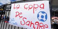 Cartaz em frente a estádio El Campin, em Bogotá, protesta contra plano de realização do evento na Colômbia: 'La copa de sangre' ('A copa de sangue')  Foto: REUTERS/Nathalia Angarita / BBC News Brasil