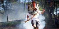 Líder indígena Kretan Kaingang chuta de volta bomba de gás lacrimogêneo lançada pela polícia contra indígenas durante protesto em frente ao Congresso  Foto: Ueslei Marcelino / Reuters