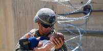 Soldado com crian&ccedil;a afeg&atilde; pr&oacute;ximo ao aeroporto de Cabul, no Afeganist&atilde;o  Foto: Nicholas Guevara / Reuters