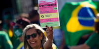 Mulher em manifestação pró-Bolsonaro segura cartaz com desenho de caixa de ivermectina  Foto: Getty Images / BBC News Brasil