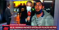 O rapaz queria passar seu recado, mas só conseguiu uns segundos de fama na tela da Jovem Pan News  Foto: Reprodução/TV